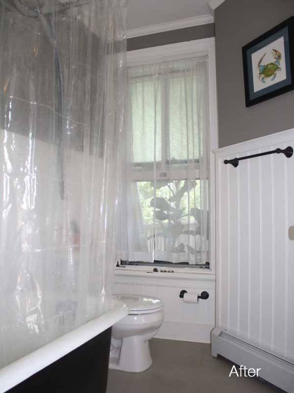 gray walls above white wainscoting in bathroom with white toilet and black painted clawfoot tub