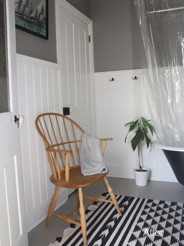 view of updated bathroom with white wainscoting and dark gray walls and a windsor chair next to closet door